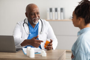 Experienced black doctor showing pills to female patient