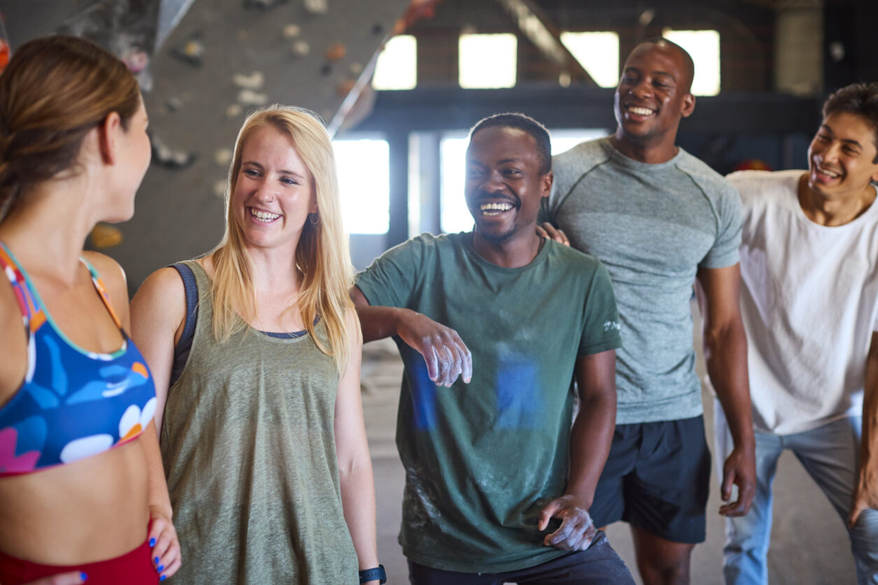 Group Of Climbers And Instructors Standing By Climbing Wall In Indoor Activity Centre