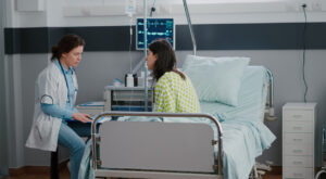 female patient sits up in hospital bed and speaks to female doctor