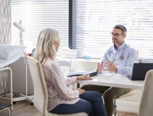 woman speaks with her primary care doctor in his office