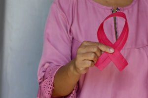 A woman holding a pink ribbon, the universal symbol for breast cancer awareness, to emphasize that Breast Cancer Awareness Month is observed annually in October